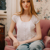 Woman sitting on a pink armchair in a room with floral wallpaper
