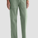 A person wearing sage green straight-leg pants with front patch pockets, shown from the waist down against a light gray studio background.