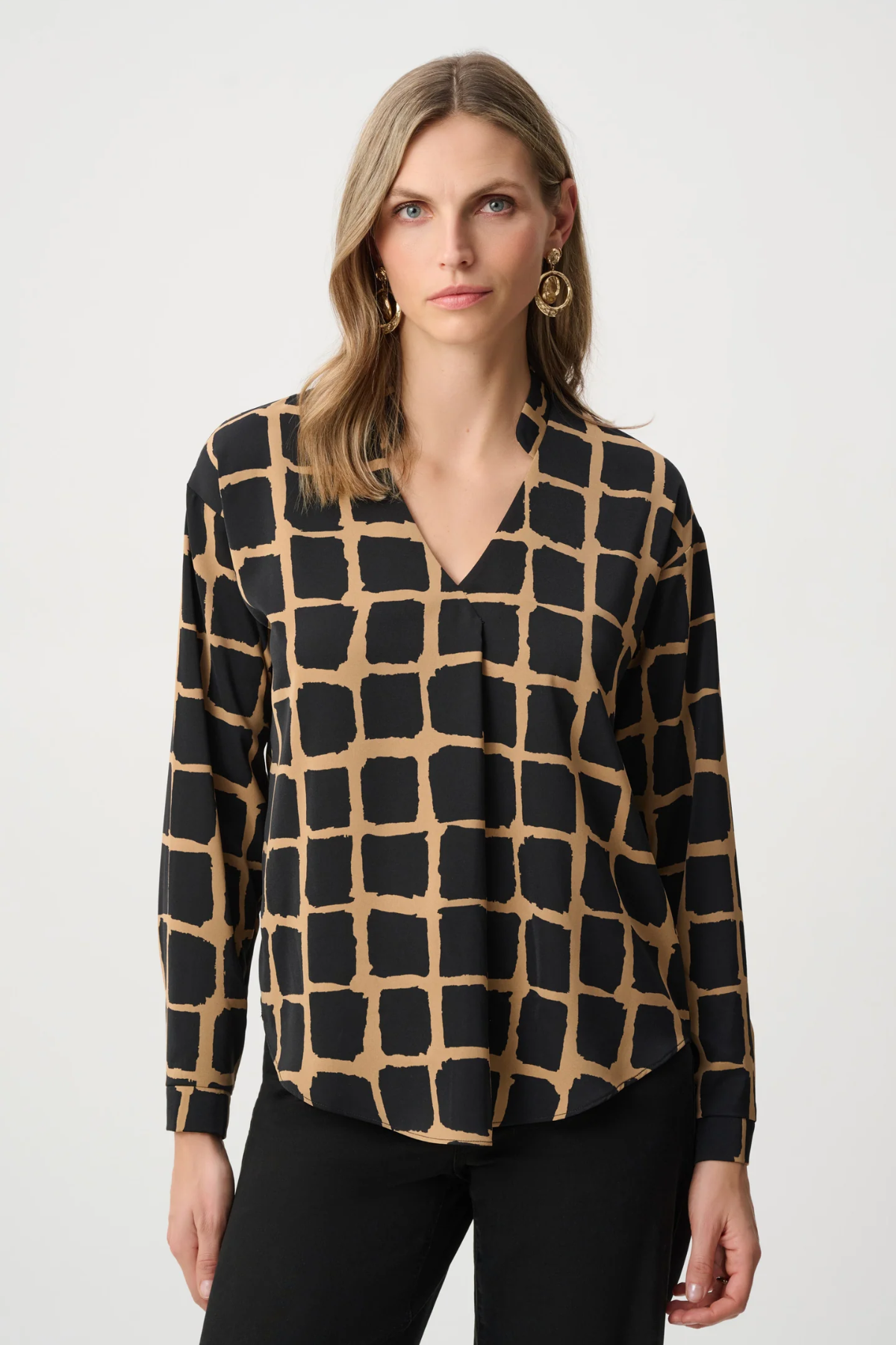 Woman wearing black and gold patterned top against a white background