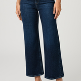 A model wearing dark blue high-waisted wide-leg cropped jeans with a faded wash, paired with beige heeled sandals, against a light gray studio background.