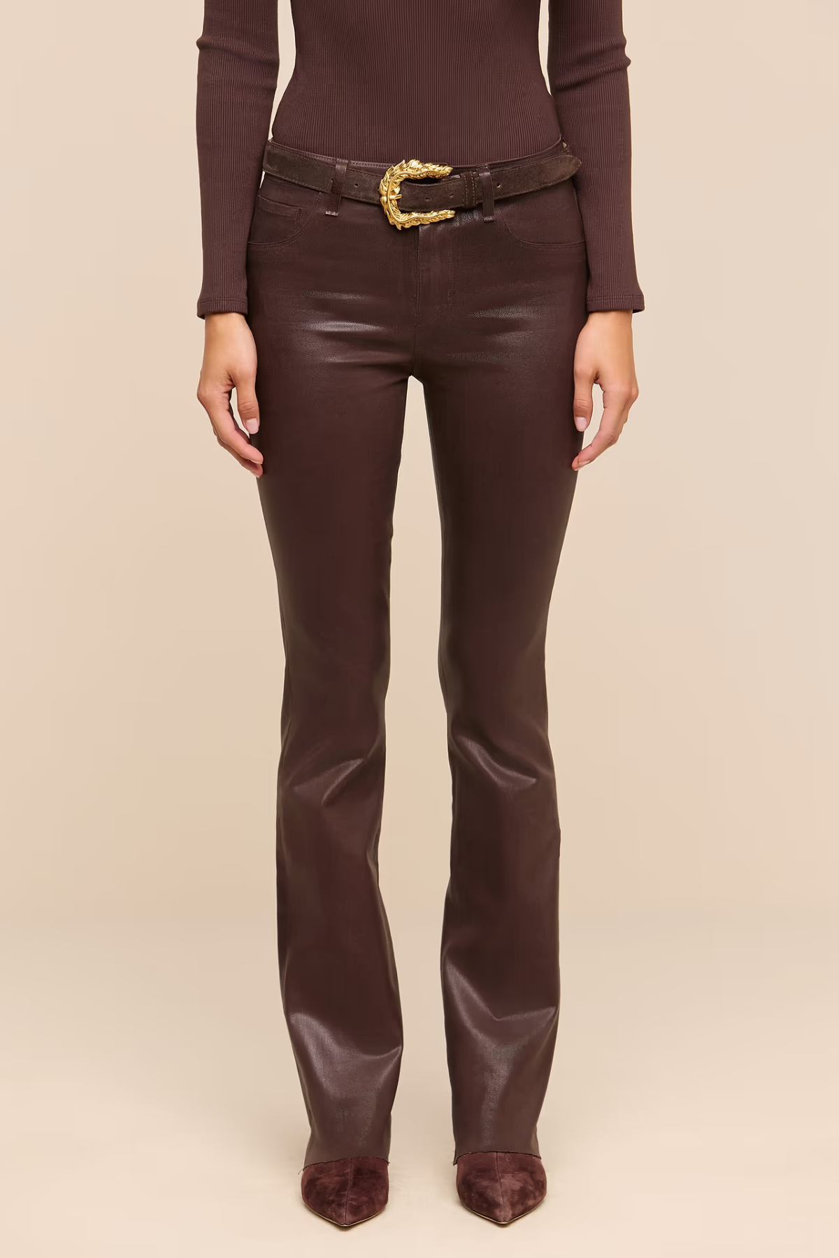 Brown coated boot cut jeans on a beige background.