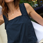 Woman wearing a navy blue sleeveless top with ruffled neckline.