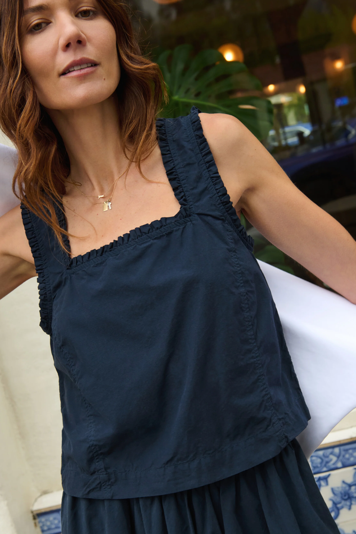 Woman wearing a navy blue sleeveless top with ruffled neckline.