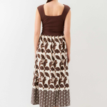 Woman wearing a brown top and patterned skirt on a white background