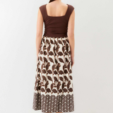 Woman wearing a brown top and patterned skirt on a white background