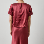 Person wearing a red satin outfit against a plain background