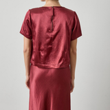 Person wearing a red satin outfit against a plain background