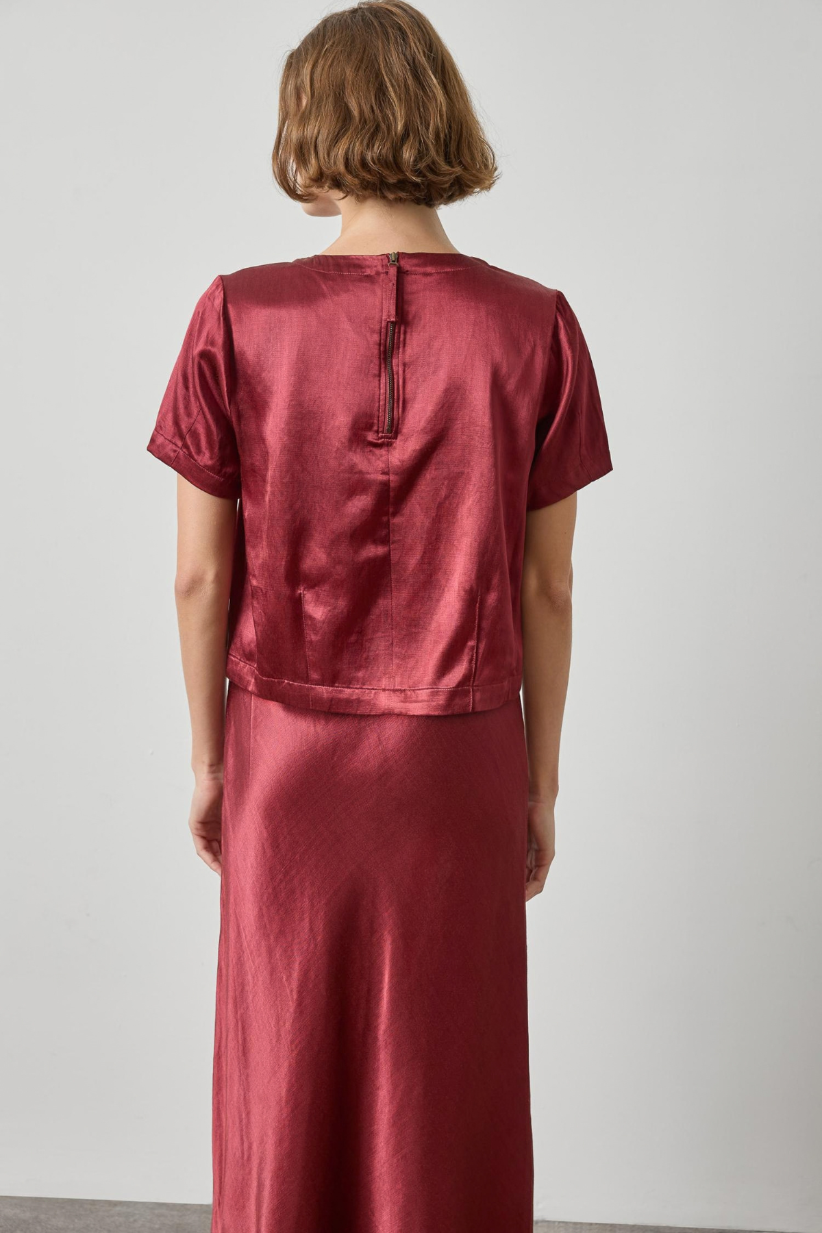 Person wearing a red satin outfit against a plain background