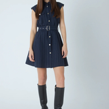 A woman modeling a sleeveless navy blue pinstriped mini dress with a matching belt and silver buckle, paired with black knee-high boots against a light gray studio background.
