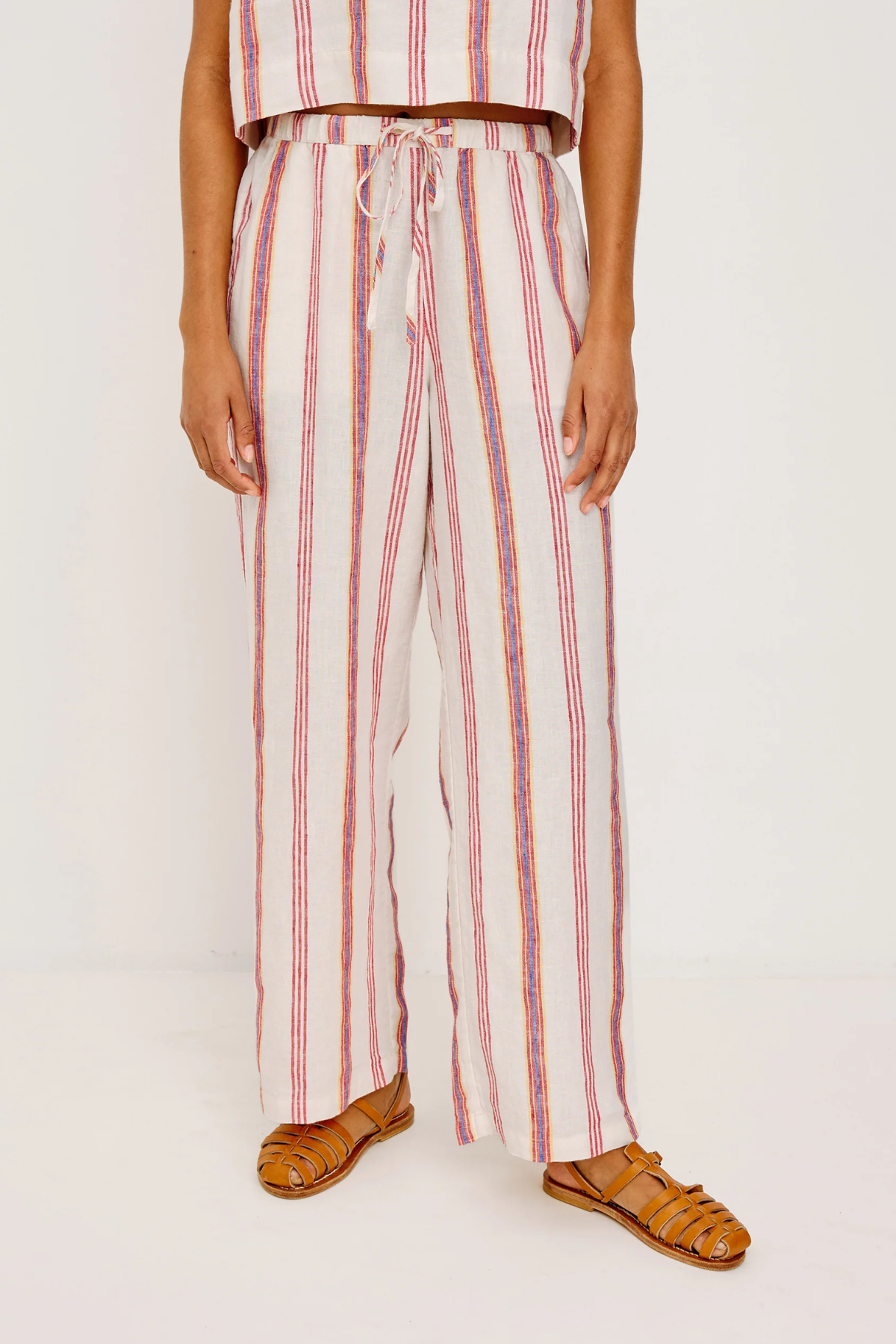 Person wearing a striped outfit with wide-leg pants on a white background
