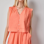 Woman wearing a coral sleeveless top and skirt set against a plain background