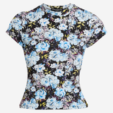A short-sleeve crewneck top featuring a dense floral print with light blue, lavender, and white flowers on a black background, displayed against a light gray studio backdrop.