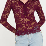 Woman wearing a burgundy lace top and light blue jeans on a white background