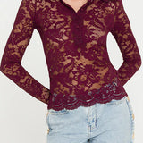 Woman wearing a burgundy lace top and light blue jeans on a white background