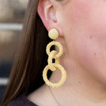 Close-up of a person wearing gold hoop earrings with a blurred background