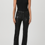 A model wearing a sleeveless black ribbed mock-neck top and black leather flare pants, standing against a light gray studio background.