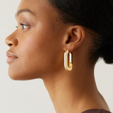 Woman wearing gold hoop earrings against a neutral background