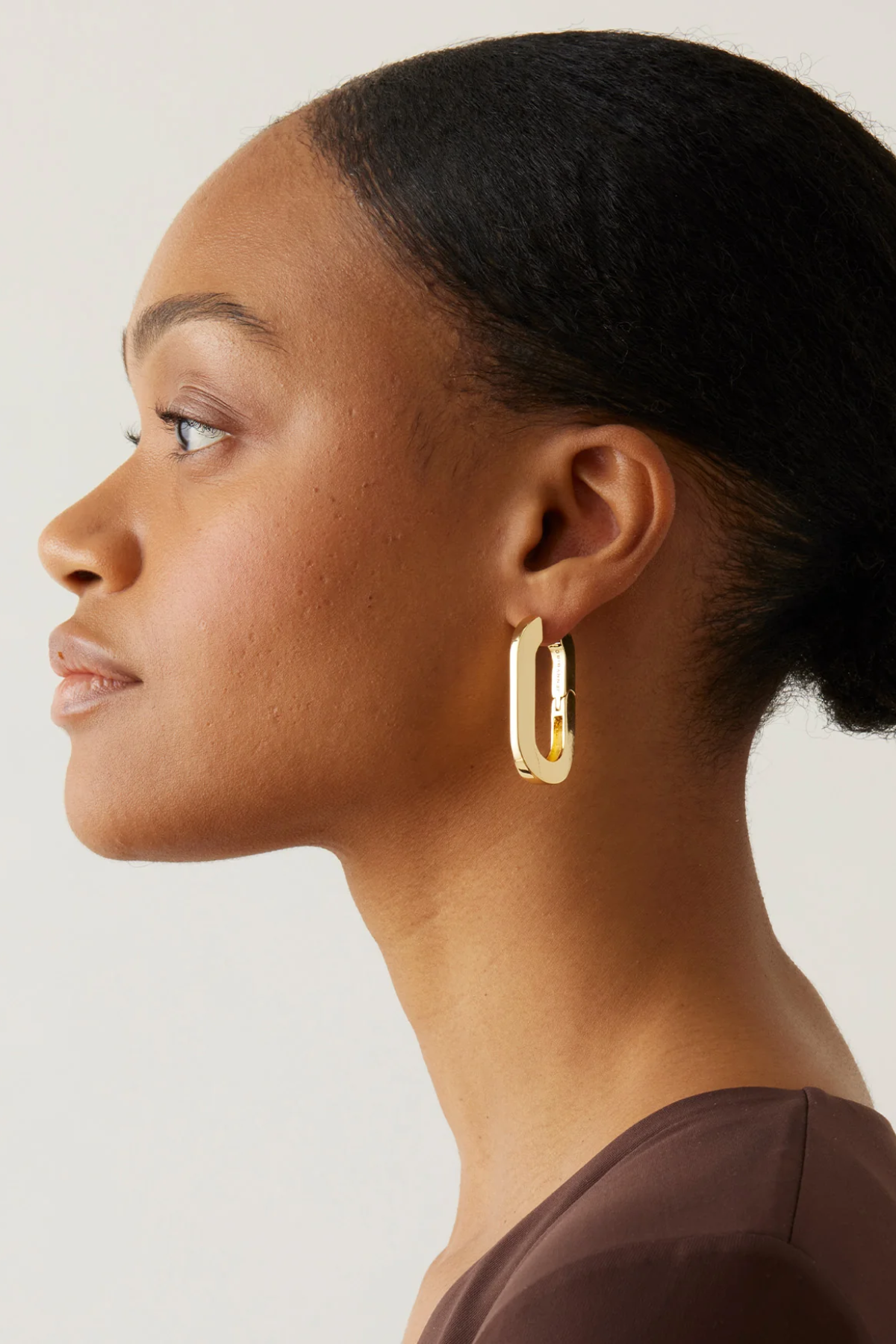 Woman wearing gold hoop earrings against a neutral background