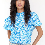 Woman wearing a blue floral top and jeans on a white background