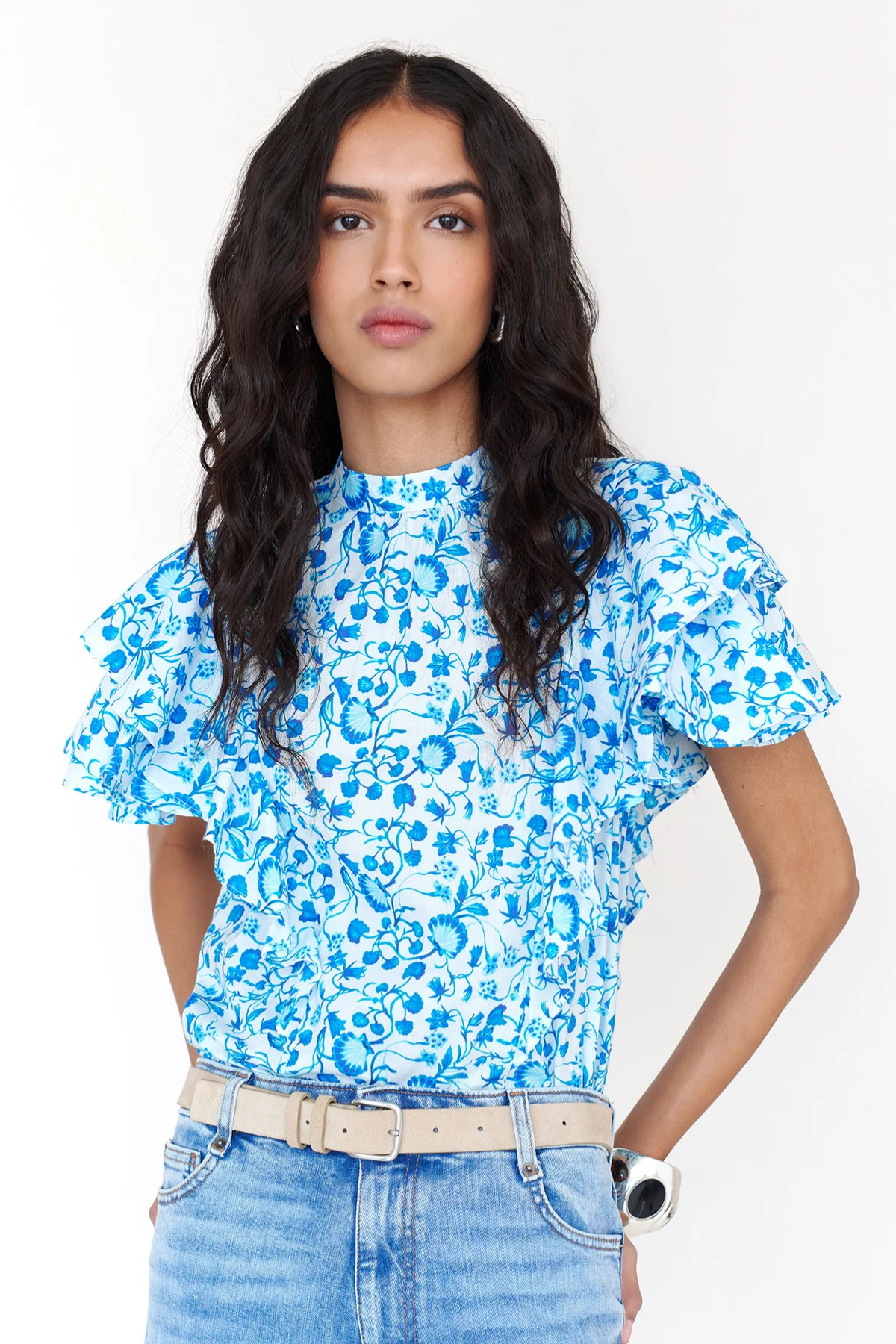Woman wearing a blue floral top and jeans on a white background