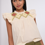 Model wearing an ivory sleeveless blouse with a relaxed fit.