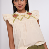 Model wearing an ivory sleeveless blouse with a relaxed fit.