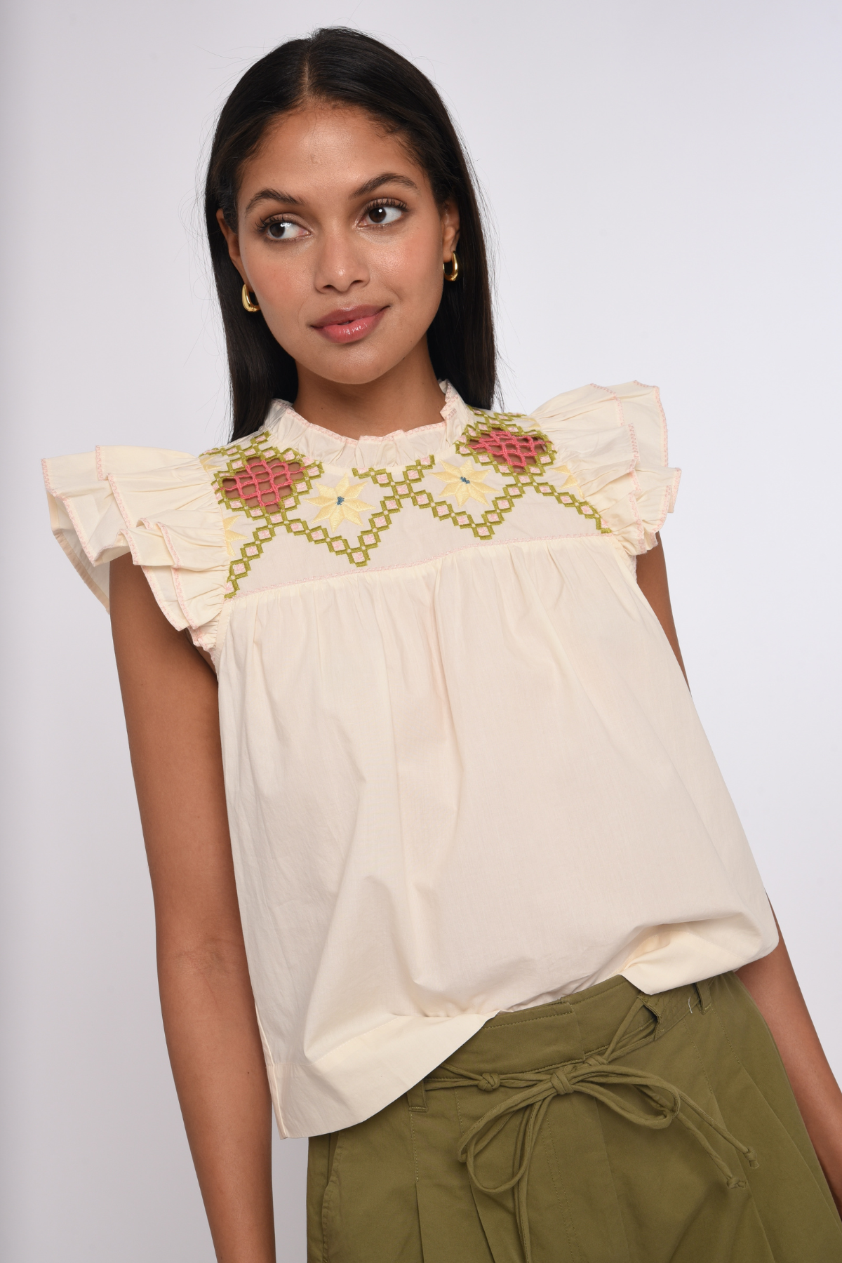 Model wearing an ivory sleeveless blouse with a relaxed fit.