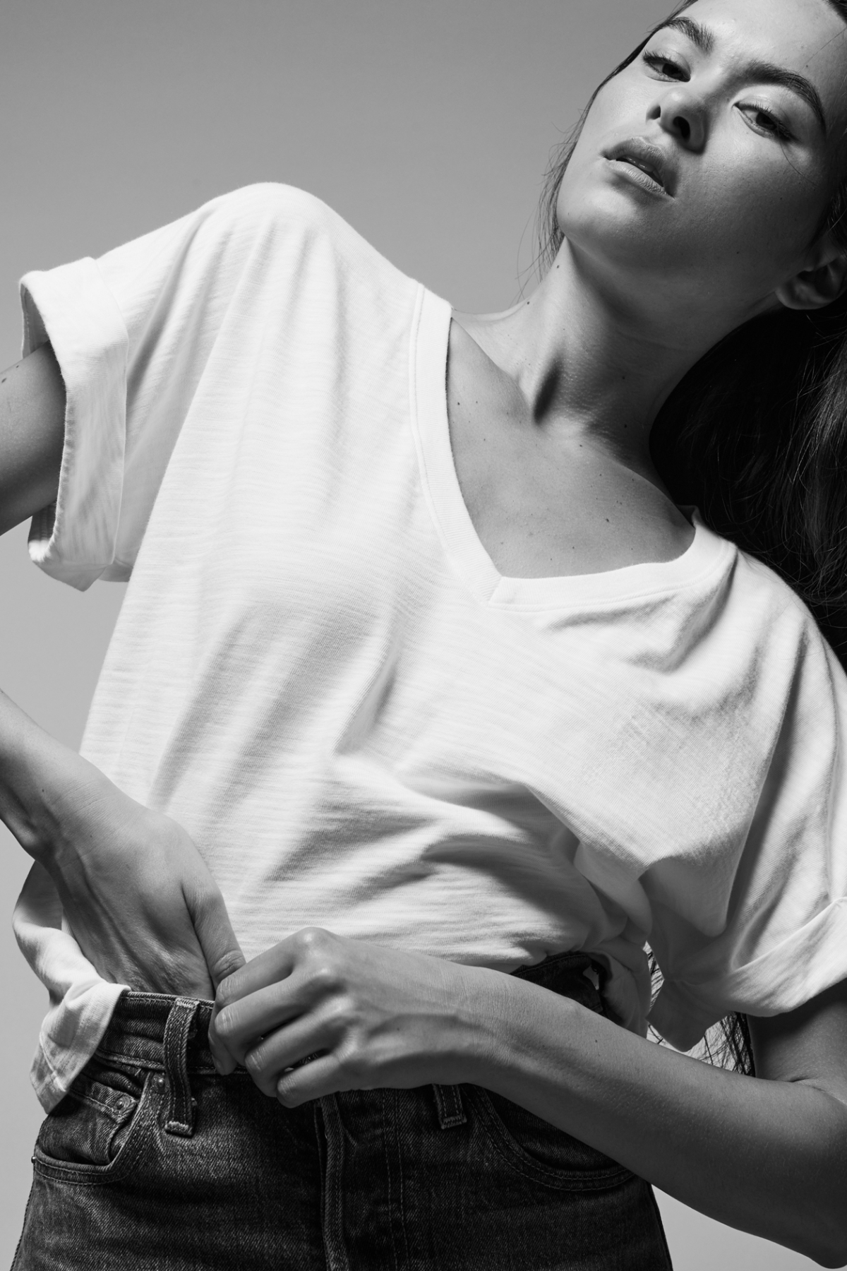 Person wearing a plain white t-shirt and dark jeans against a neutral background