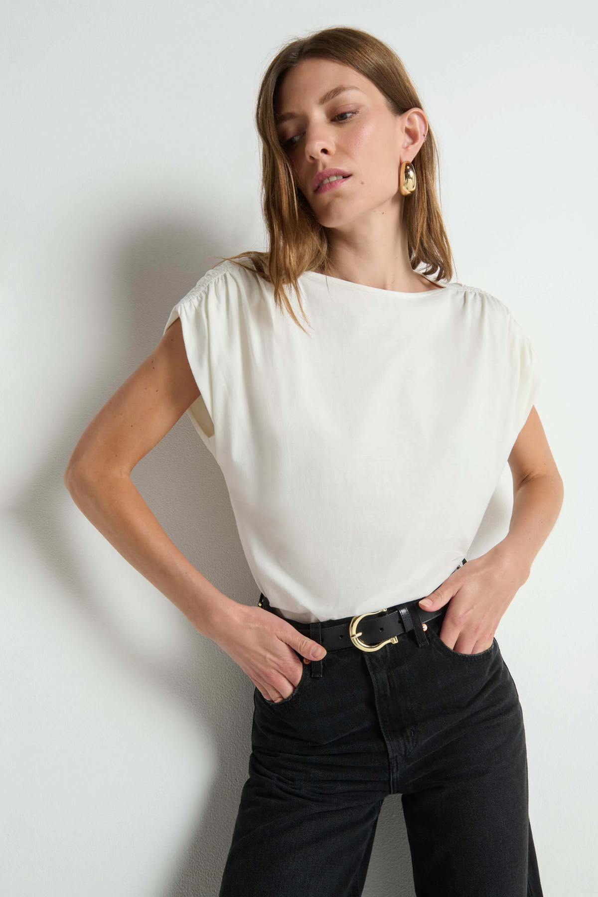 Woman wearing a white top and black pants against a plain background