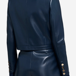 A model shown from the back wearing a dark navy faux-leather cropped jacket and matching shorts, featuring gold button details on the cuffs.