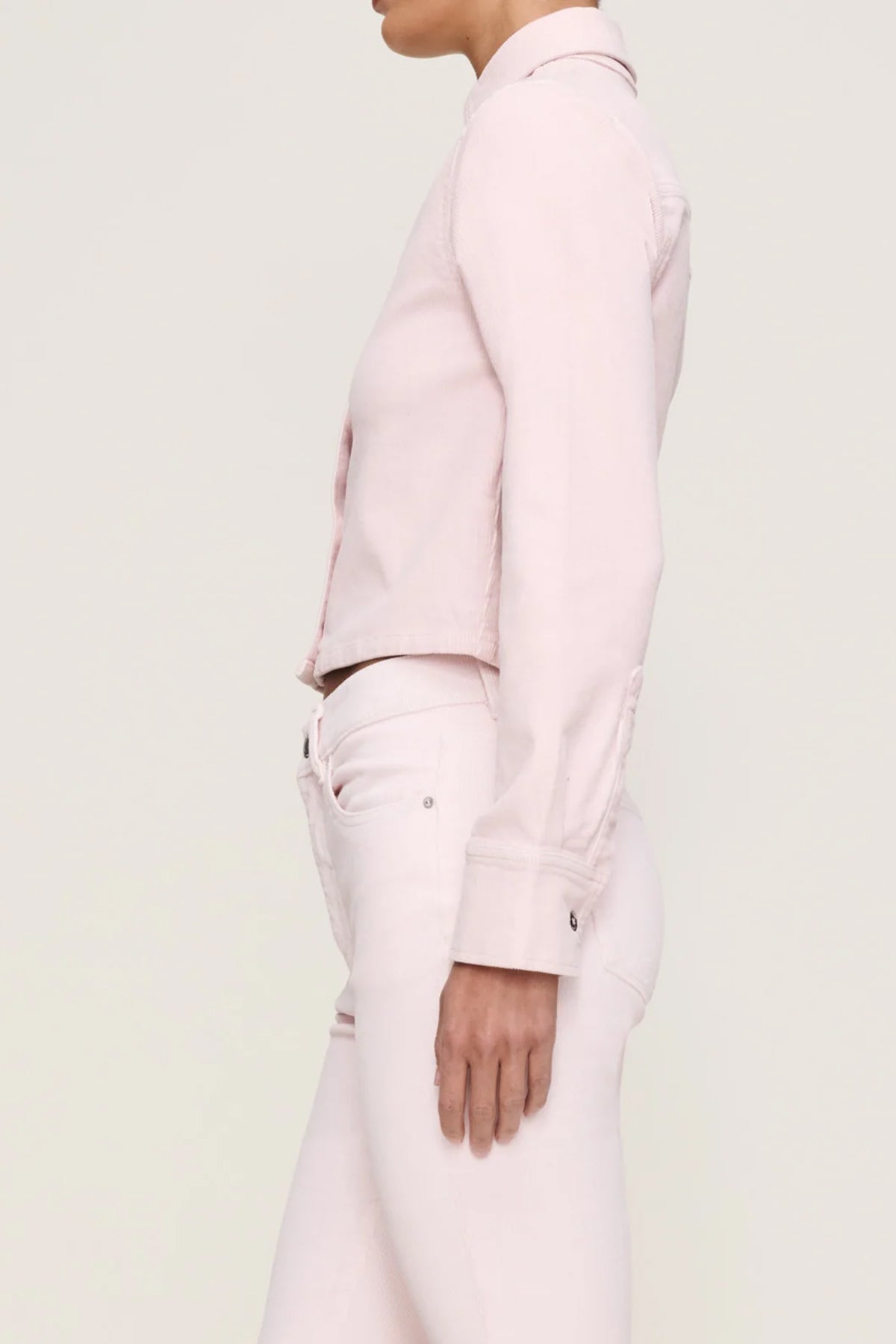 Person wearing a light pink shirt and matching pants on a light gray background