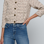 Model wearing a tweed jacket with jeans on and off white background.