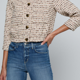 Model wearing a tweed jacket with jeans on and off white background.