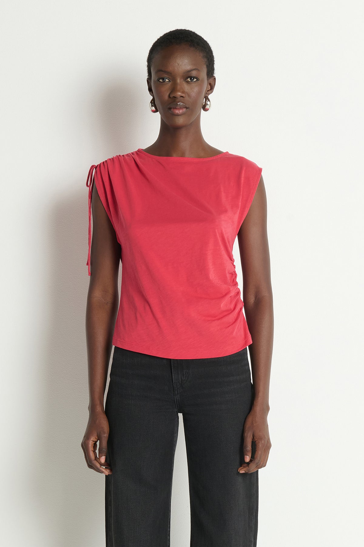 Woman wearing a pink top and black pants against a white background