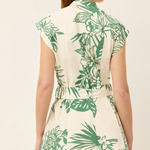 Woman wearing a white dress with green leaf pattern on a plain background