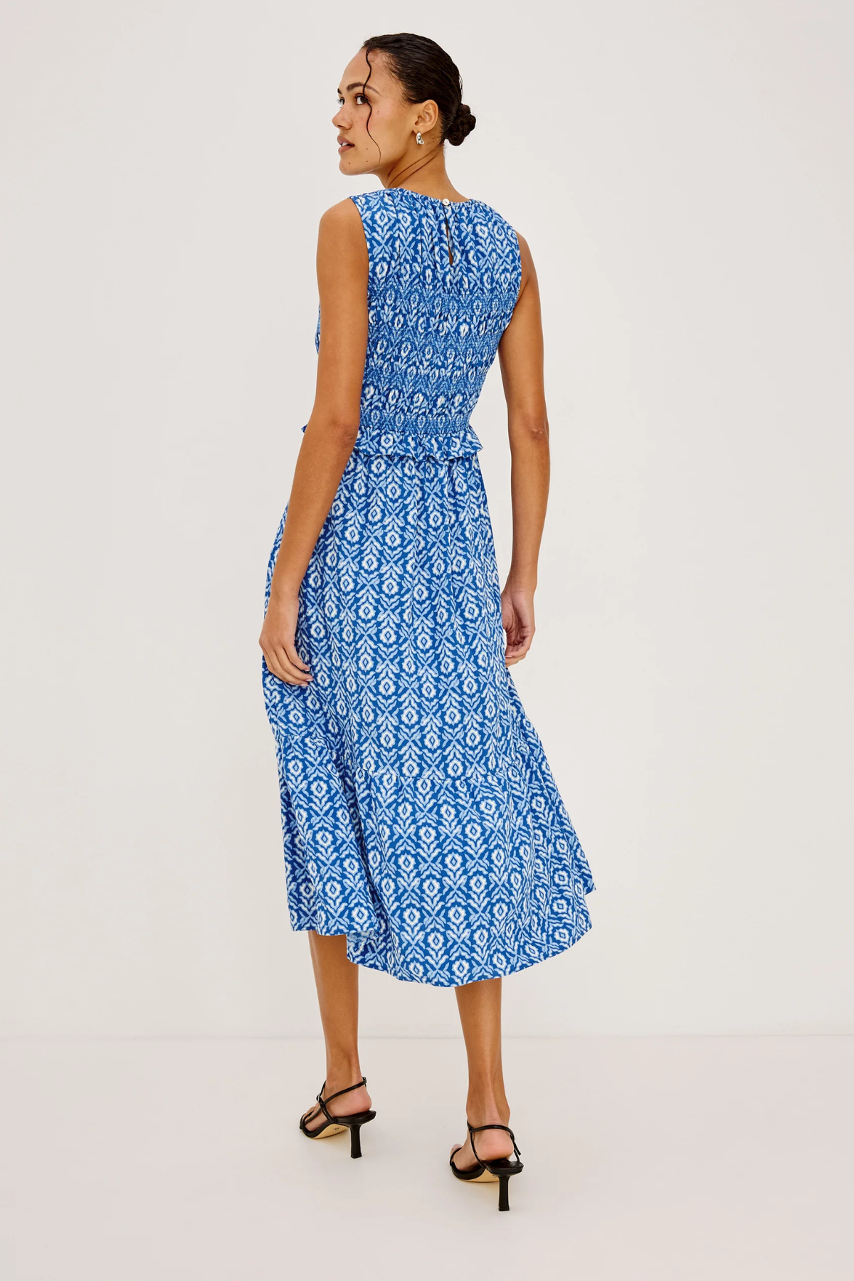 Woman wearing a blue patterned dress on a light gray background