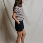 Person wearing a striped shirt and dark shorts against a plain background