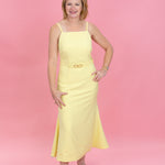 Woman wearing a yellow dress against a pink background