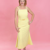 Woman wearing a yellow dress against a pink background