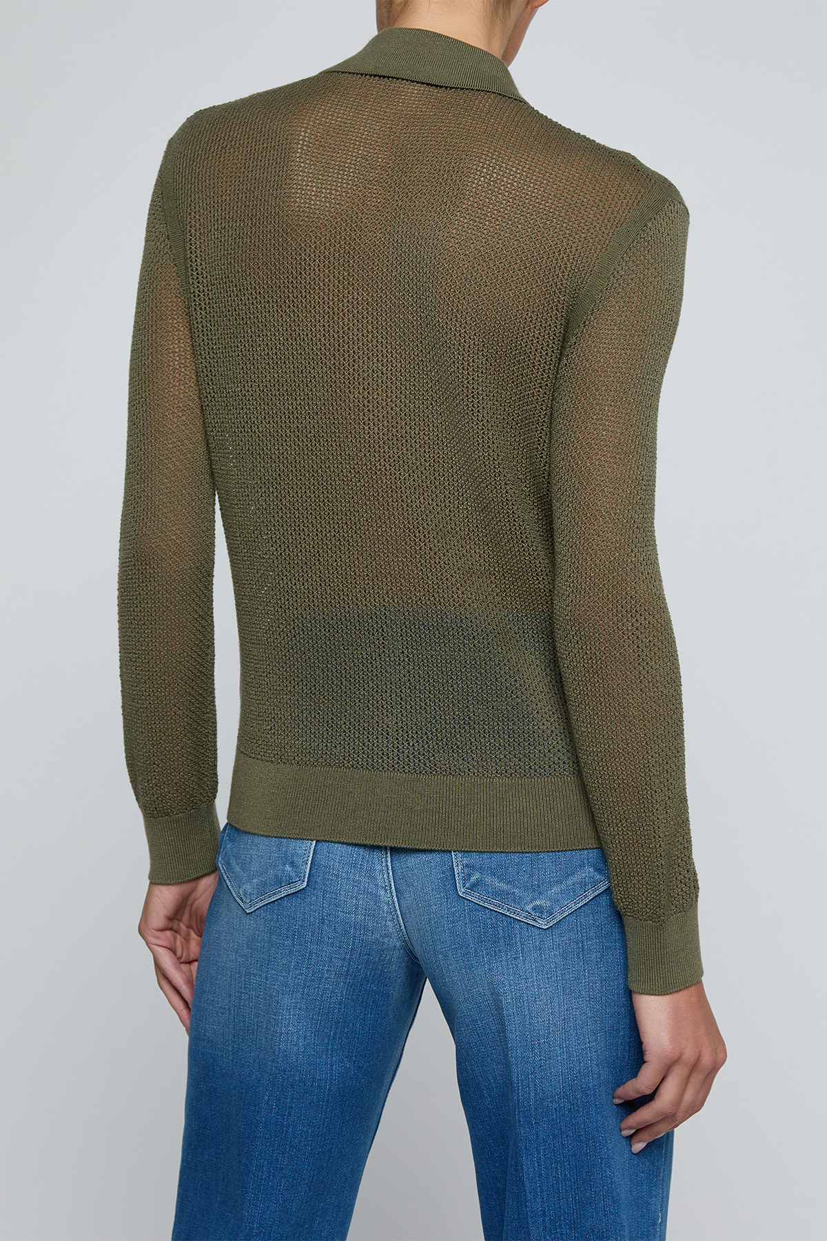 Model wearing a green knit button front sweater top with jeans on an off white background.