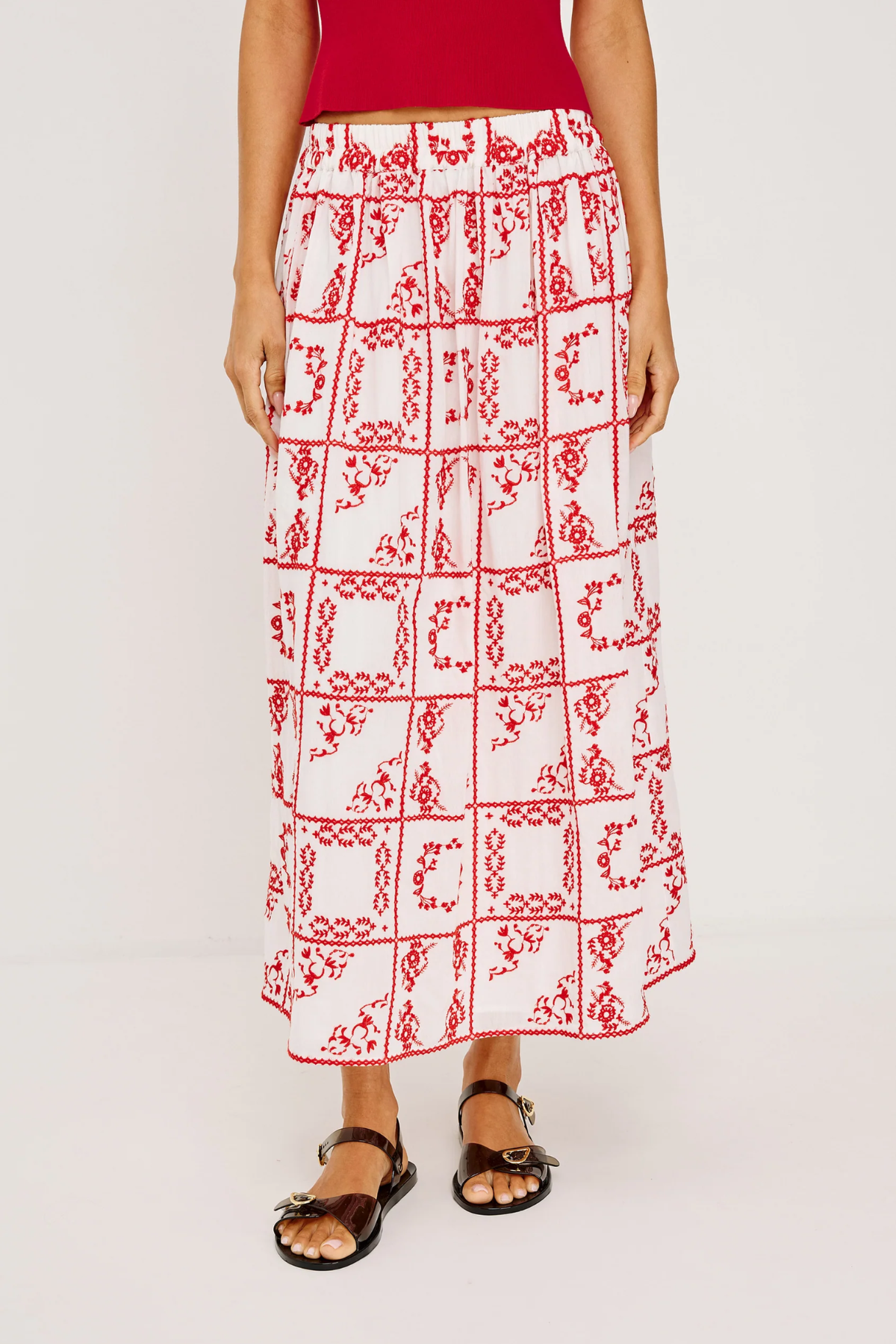 Person wearing a red and white patterned skirt on a plain background