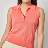 Woman wearing a coral sleeveless polo shirt against a plain background