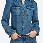 A woman wearing a blue denim long-sleeve button-up shirt with chest flap pockets and matching embellished jeans, shown against a plain light background.