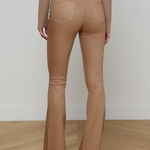 Person wearing tan flared pants and a matching top on a plain background