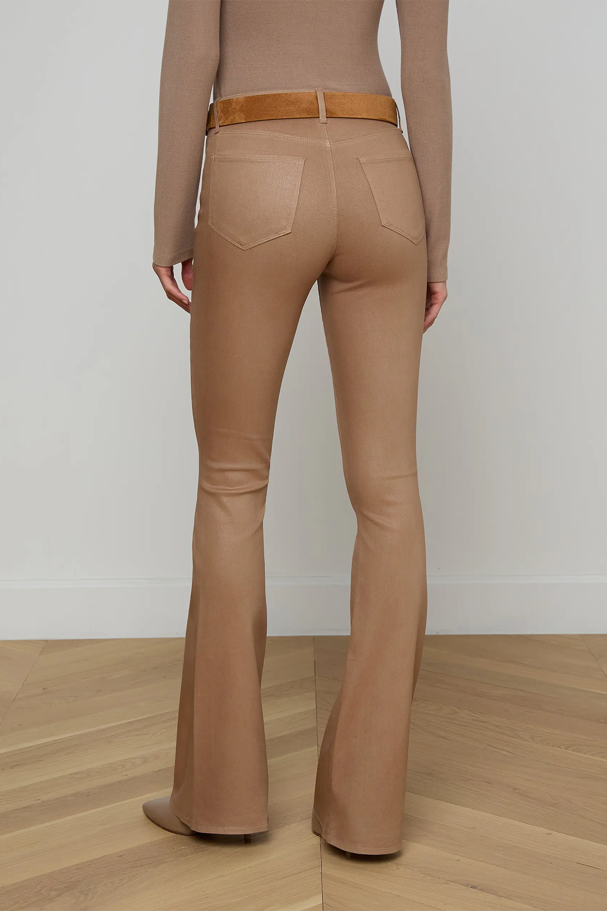 Person wearing tan flared pants and a matching top on a plain background