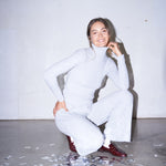 Woman wearing light grey knit pants with a straight leg silhouette, styled in soft studio lighting.