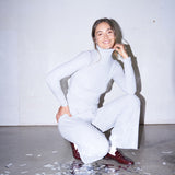 Woman wearing light grey knit pants with a straight leg silhouette, styled in soft studio lighting.