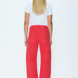 A woman viewed from the back wearing bright red wide-leg cropped pants, a white short-sleeve T-shirt, and red strappy heels against a plain white studio background.