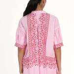 Woman wearing a pink embroidered traditional outfit on a white background