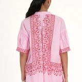 Woman wearing a pink embroidered traditional outfit on a white background